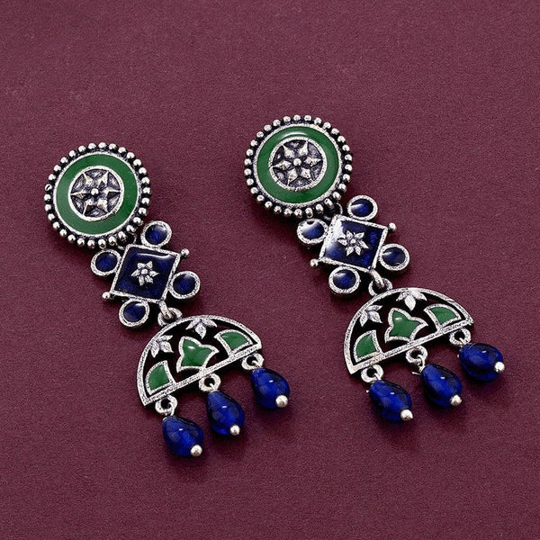 Pair of decorative earrings with green and blue elements on a maroon background