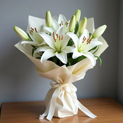 Bouquet of white lilies wrapped in beige paper on a wooden surface 