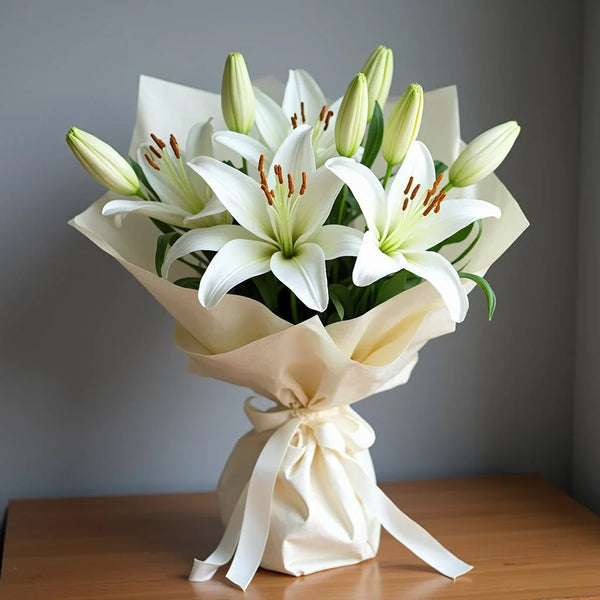 Bouquet of white lilies wrapped in beige paper on a wooden surface 