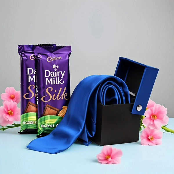 Blue silk tie in gift box with Dairy Milk Silk chocolates and pink flowers, gift set arrangement