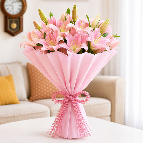 Bouquet of pink lilies wrapped in pink paper with a bow on a table in a living room.