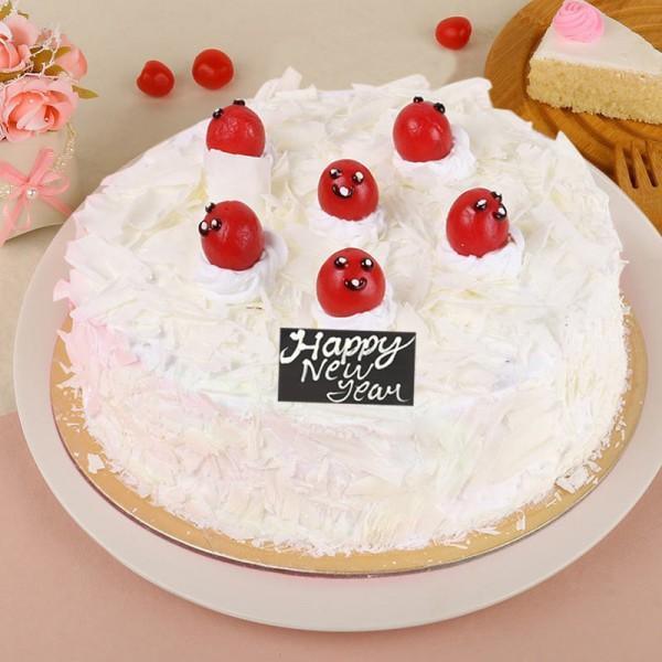 White frosted cake with red cherries and 'Happy New Year' sign on a beige background