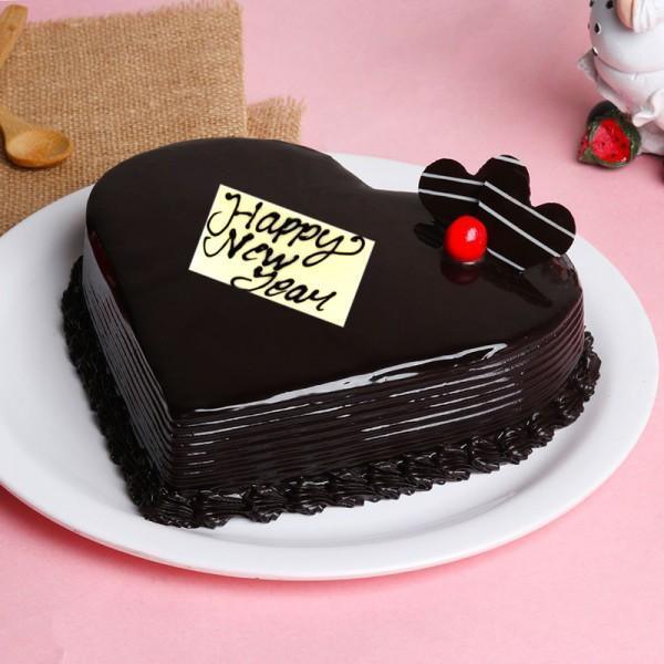 Heart-shaped chocolate cake with 'Happy New Year' message on a pink background