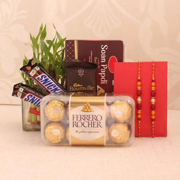 Gift basket with Ferrero Rocher, Snickers, Cadbury, and Soan Papdi with two red ribbons on a beige background.