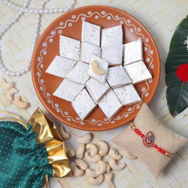 Decorative plate with white square treats, cashews, and a small decorative item on a textured surface.