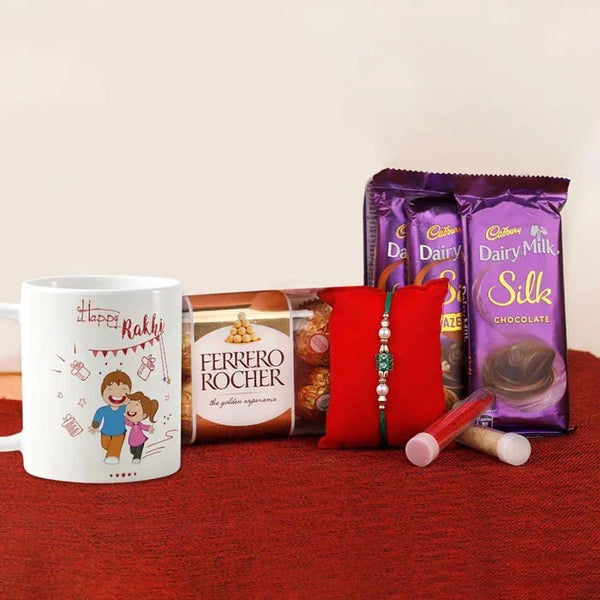 Gifting set with a mug, Ferrero Rocher, Dairy Milk, and a red rakhi on a red surface.