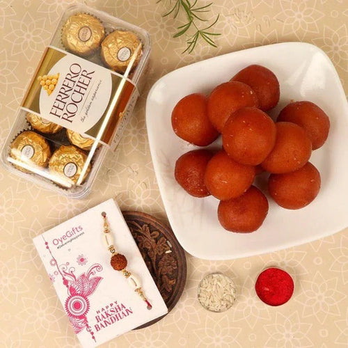 Ferrero Rocher chocolates, a bowl of red sweets, and a Rakhi with a card on a decorative background.