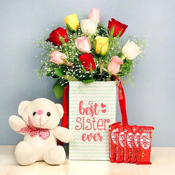 Bouquet of colorful roses, teddy bear, and chocolate bars with 'best sister ever' card on a light gray background