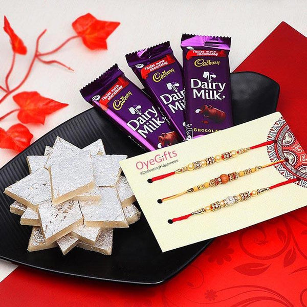 Cadbury Dairy Milk chocolate bars with cookies and Rakhi on a decorative plate.
