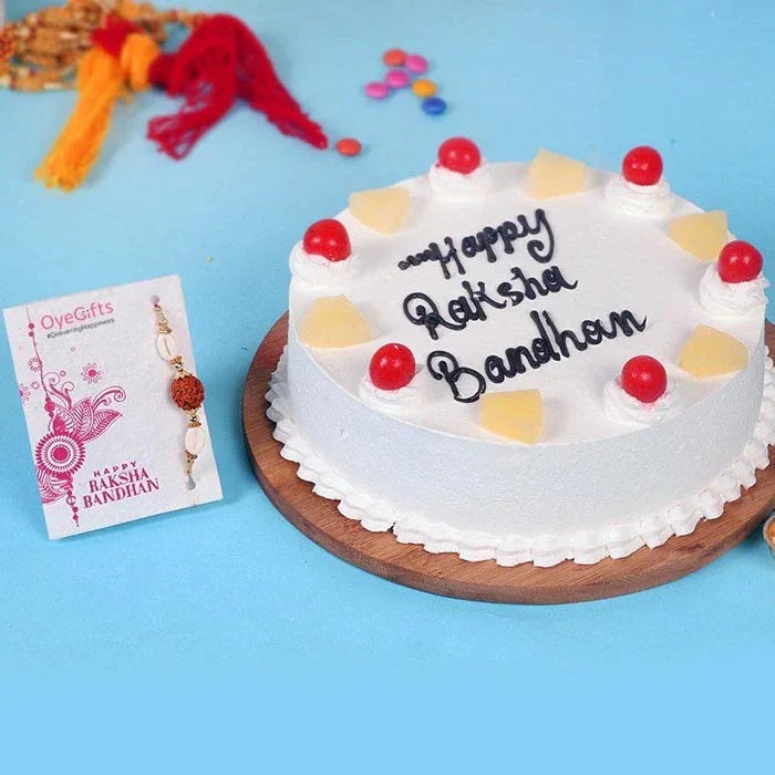 White cake with 'Happy Raksha Bandhan' text on a blue background with decorative items.