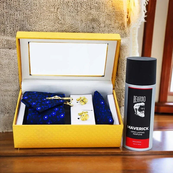 Gift set with blue bow tie, gold tie clip, and 'Beardo Maverick' perfume bottle on a wooden surface.