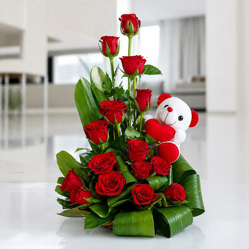 Bouquet of red roses with a small teddy bear toy in a modern indoor setting