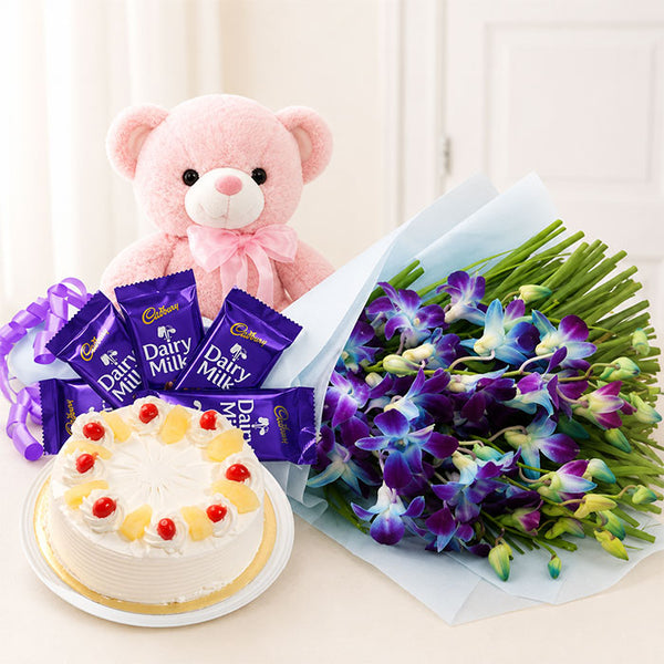 Bouquet of flowers, cake, and teddy bear with Cadbury Dairy Milk chocolate bars on a white background