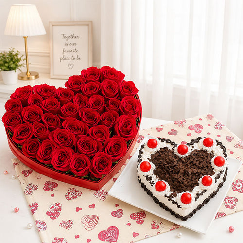 Heart-shaped arrangement of red roses and a heart-shaped chocolate cake on a decorative tablecloth.