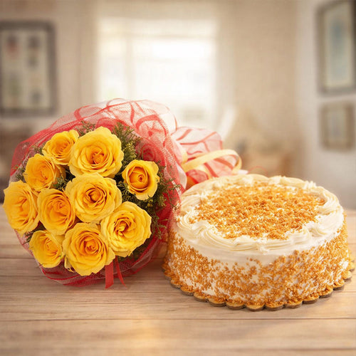 Bouquet of yellow roses and a round cake on a wooden surface with a blurred indoor background.