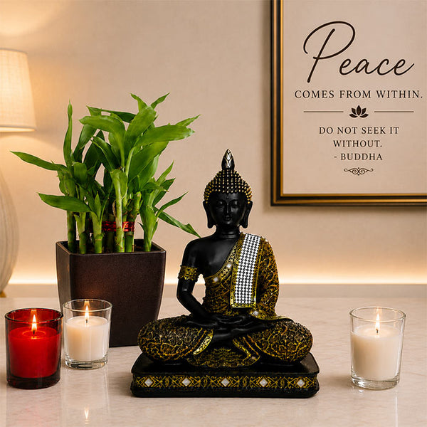 Decorative setup with a Buddha statue, candles, and a bamboo plant on a table.