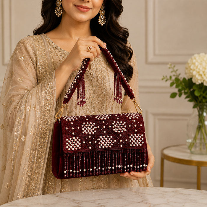 Woman holding a maroon beaded handbag 