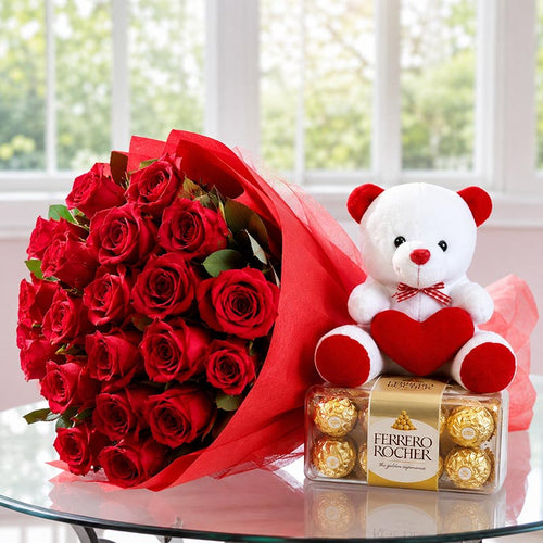 Bouquet of red roses, teddy bear with a heart, and Ferrero Rocher chocolates on a glass table.