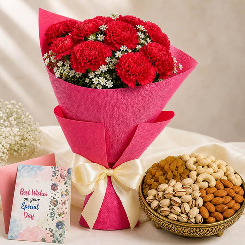 Bouquet of red flowers wrapped in pink paper with a bowl of nuts and a card on a light background
