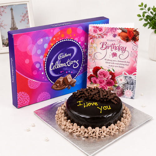 Chocolate cake with 'I Love You' message, Cadbury chocolate bar, and birthday card on a white surface.