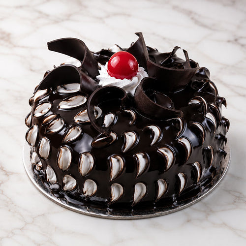 Chocolate cake with white frosting and a cherry on top, placed on a marble surface.