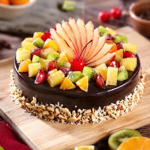 Fruit-topped chocolate cake on a wooden board with a blurred background
