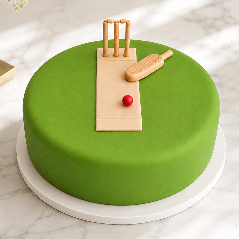 Green cake with cricket-themed decorations on a marble surface