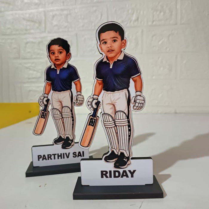 Two cut-out figures of children in cricket gear with nameplates on a white background