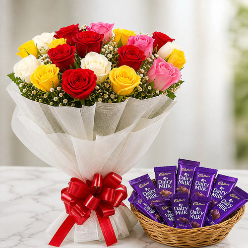 Bouquet of colorful roses with a basket of Cadbury Dairy Milk chocolate bars on a marble surface.