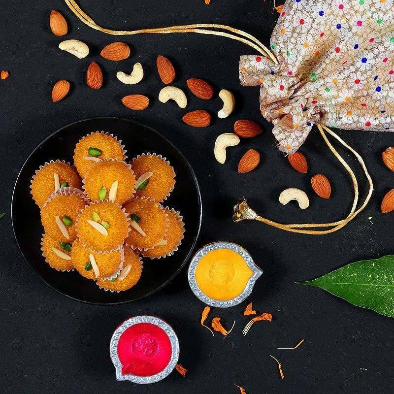 Assorted snacks including cookies, nuts, and colorful lamps on a black surface with a decorative bag.