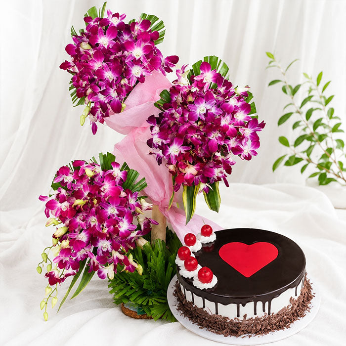 Chocolate cake with a red heart and a bouquet of purple flowers on a white background