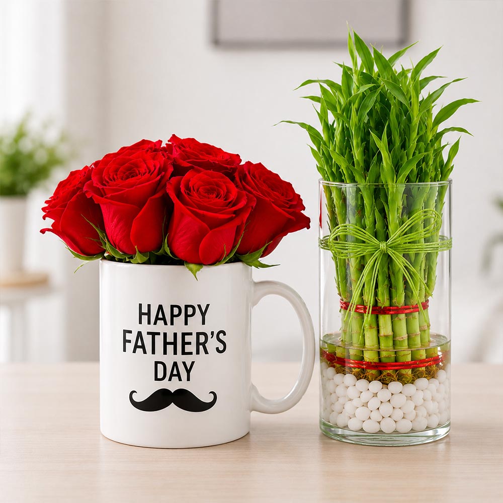 White mug with red roses and 'Happy Father's Day' text, next to a glass vase with green bamboo plant on a light surface.