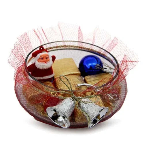 Glass bowl with chocolates, Santa figurine, blue ornament, and silver bells in festive wrapping