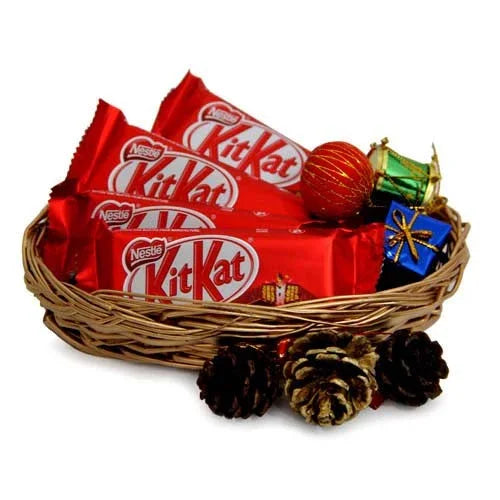 Basket with KitKat chocolate bars, festive decor, pine cones and gift boxes for gifting