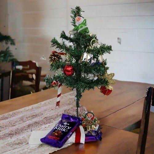 Mini Christmas tree with ornaments, Dairy Milk chocolates, and gift box on a table