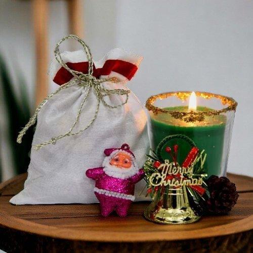 Christmas gift set with green candle, Merry Christmas sign, Santa figurine, and white pouch