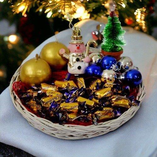 Festive gift basket with chocolates, Christmas ornaments, snowman and mini Christmas tree decor