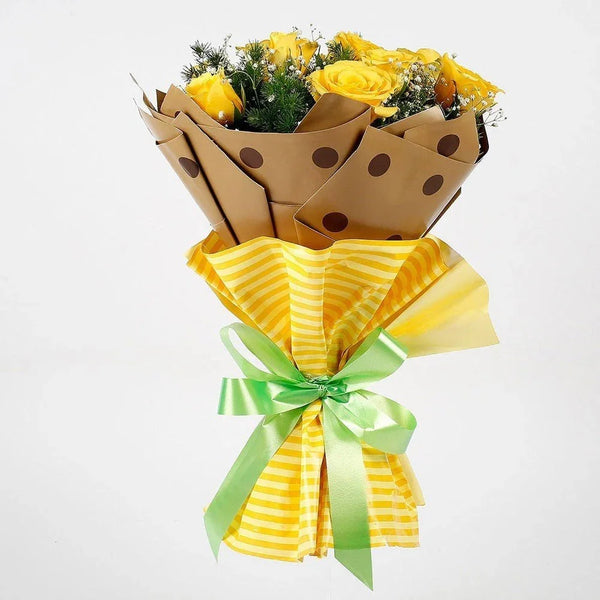 Yellow rose bouquet wrapped in polka dot paper and yellow striped sheet, tied with a green ribbon