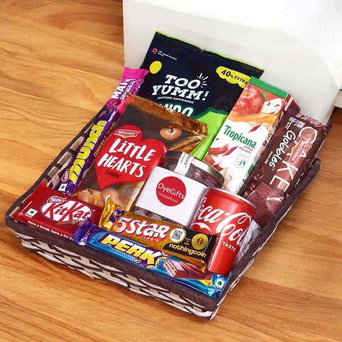 Assorted snacks and drinks in a box on a wooden surface