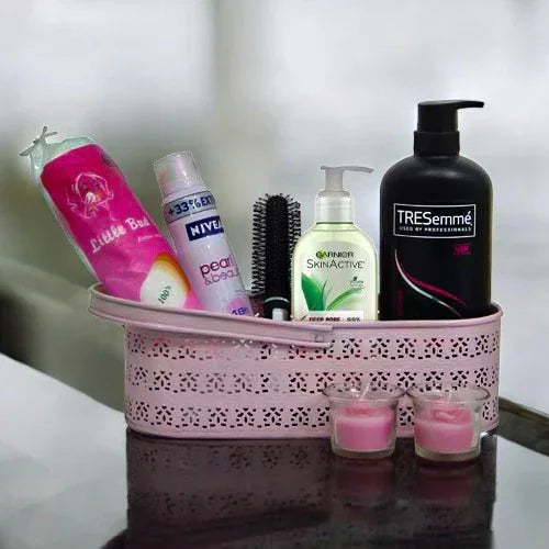Women’s grooming kit with body lotion, face wash, hairbrush, shampoo, and pink candles in a basket