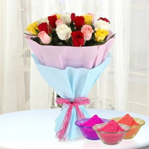 Bouquet of multicolored roses wrapped in light blue paper with a pink ribbon, placed on a white surface with Holi colors in small bowls.