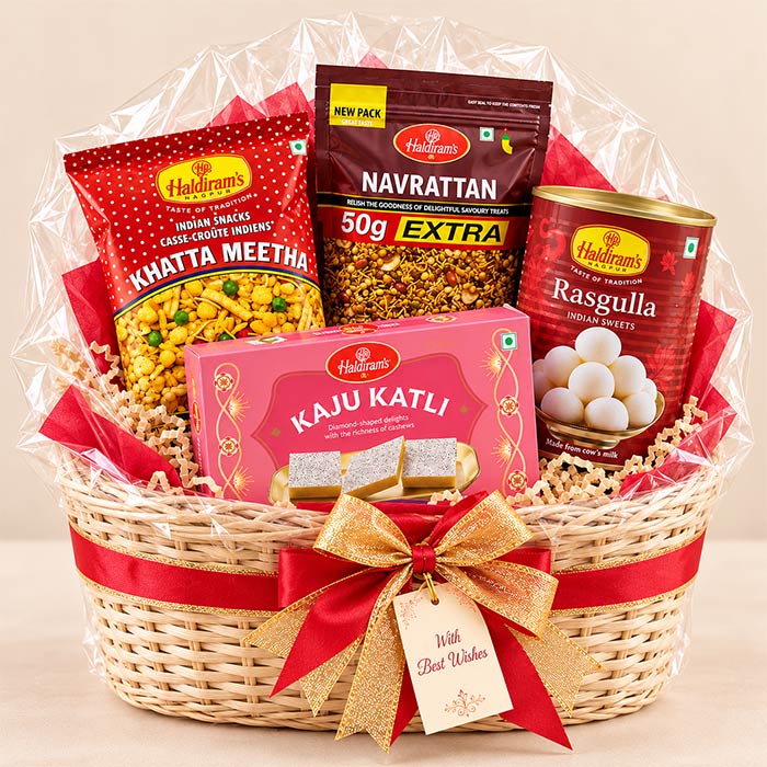 A Haidilaoi gift basket filled with assorted Indian snacks, wrapped in clear cellophane and tied with a red ribbon and gold bow. Visible items include Khattra Meetha, Navrattan Extra, Kasu Katli, and Rasgulla.