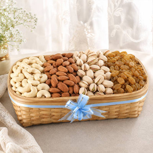 Basket of assorted nuts and dried fruits with a decorative bow on a neutral background