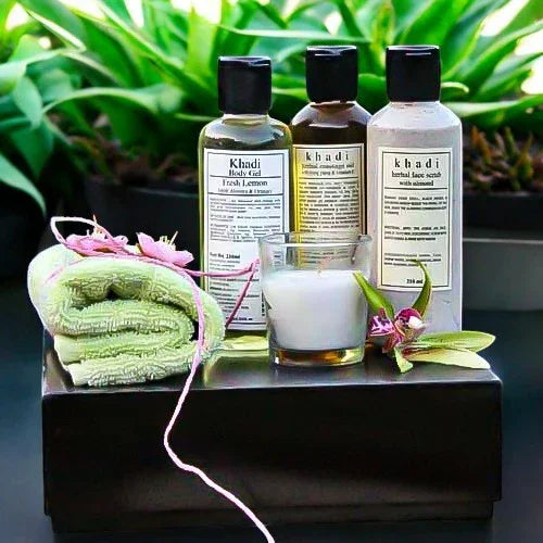 Herbal skincare gift set with khadi body wash, face wash, towel, and candle, plants in background