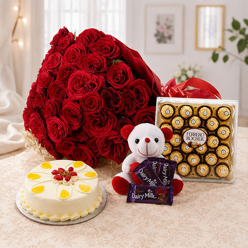 Bouquet of red roses, a cake, a teddy bear with chocolates, and a box of Ferrero Rocher chocolates on a table.
