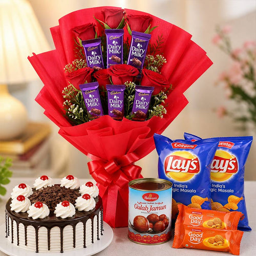 Bouquet of red roses with Dairy Milk chocolate bars, a cake, Gulab Jamun, and Lay's potato chips on a table.