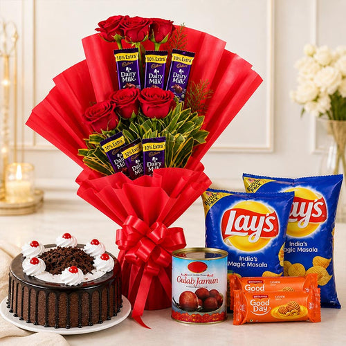 Bouquet of red roses with Dairy Milk chocolates, a chocolate cake, Gulab Jamun, and Lay's potato chips on a table.