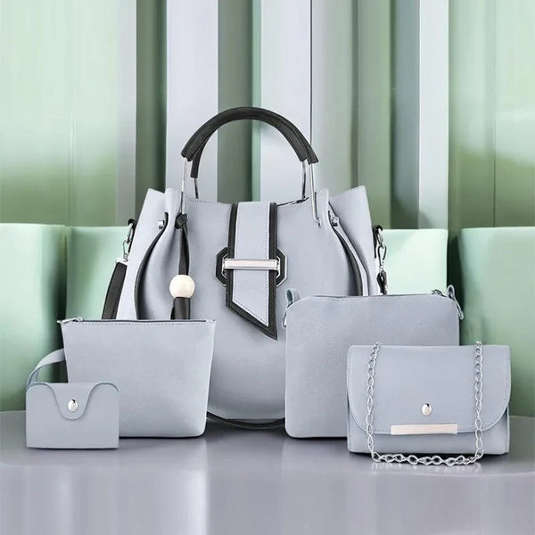 Set of gray handbags with different sizes on a light gray surface with a green and white striped background.