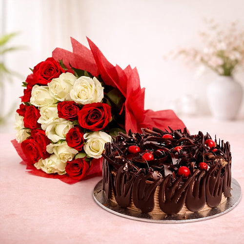 Chocolate cake with red berries and a bouquet of red and white roses on a light pink surface.