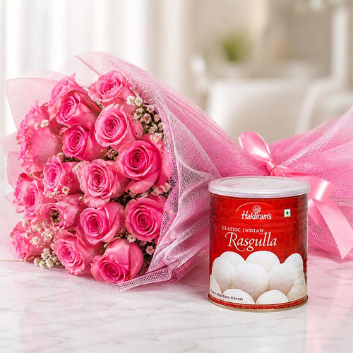 Bouquet of pink roses with a Haldiram's Rasgulla can on a white surface.